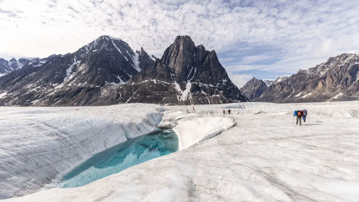 The team walk past a huge meltwater lake on the Edward Bailey Glacier.  (photo credit: National Geographic/Pablo Durana)