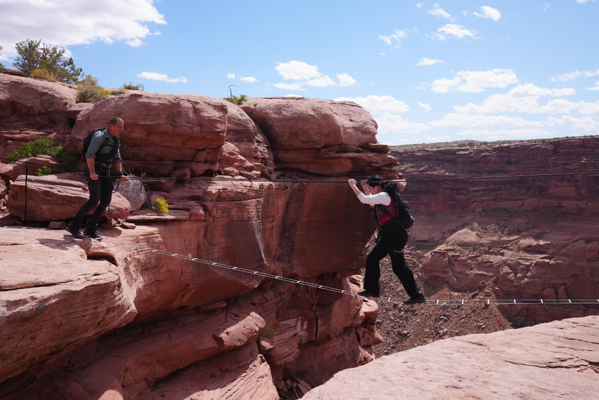 Elizabeth Tabish walking across a rope bridge with Bear Grylls
