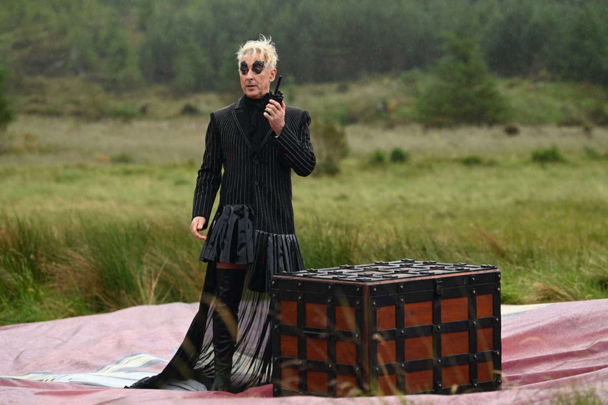 Alan Cumming hosting The Traitors in a black suit